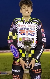 Sam: young man wearing speedway jumpsuit smiling holding an award