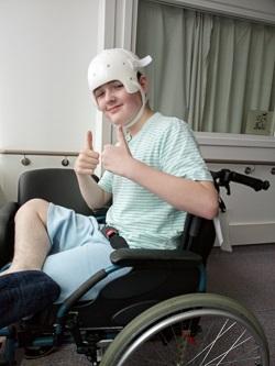 Spike sitting in his wheelchair in hospital with a helmet on