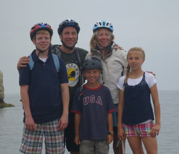 Chas: family in front of the sea wearing cycling helmets