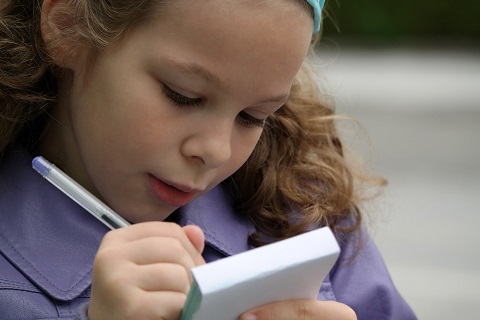young girl writes down notes in a notebook