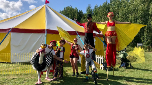 Circus entertainers in front of a big top tent.