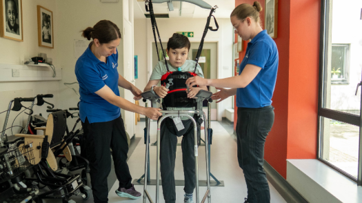 Leo in a therapy session using the Guldmann Hoist with therapists