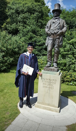 Saqlain celebrating his graduation, standing in his cap and gown