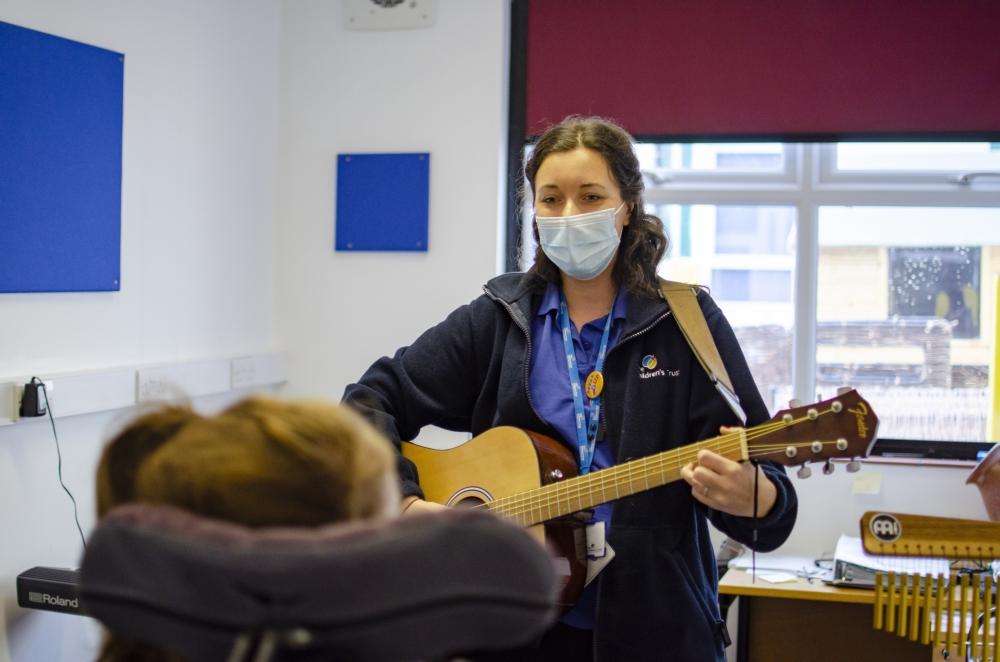 Music therapist playing a guitar in front of a young person