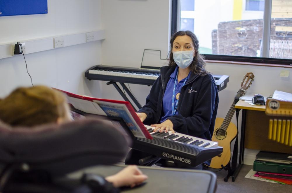 Music therapist playing a keyboard in front of a young person