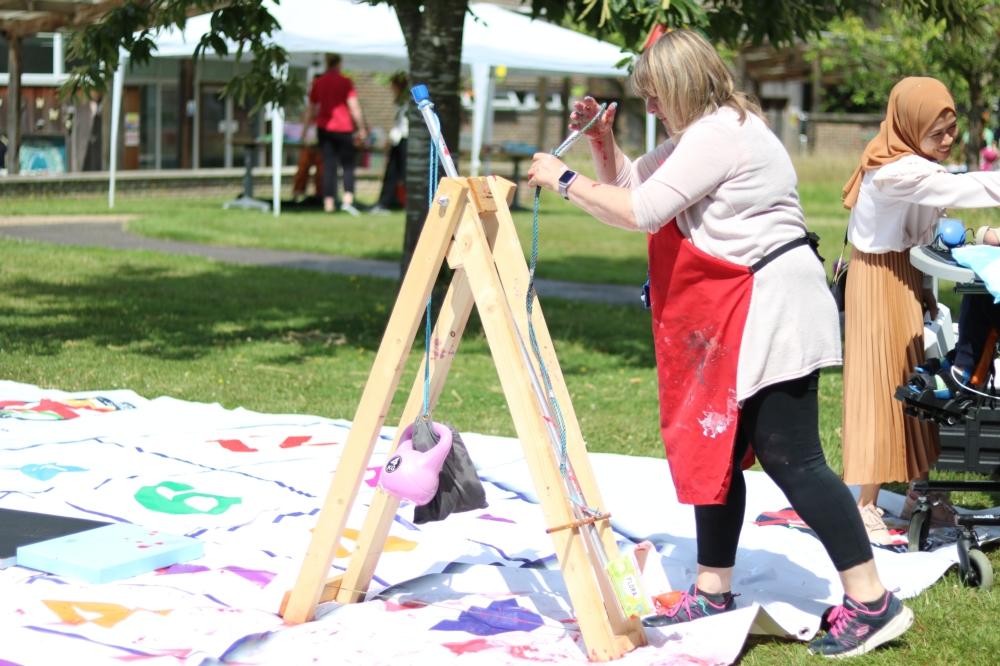 Outdoors. A person reloading paint onto a wooden catapult.