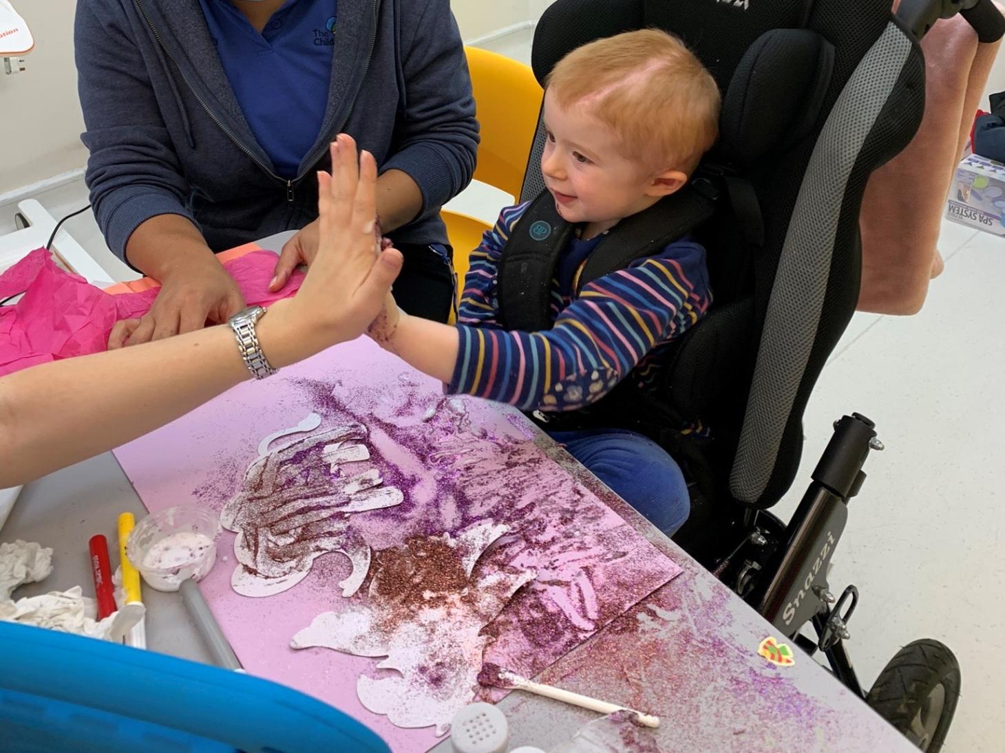 Millie doing arts and crafts, giving an adult a high five