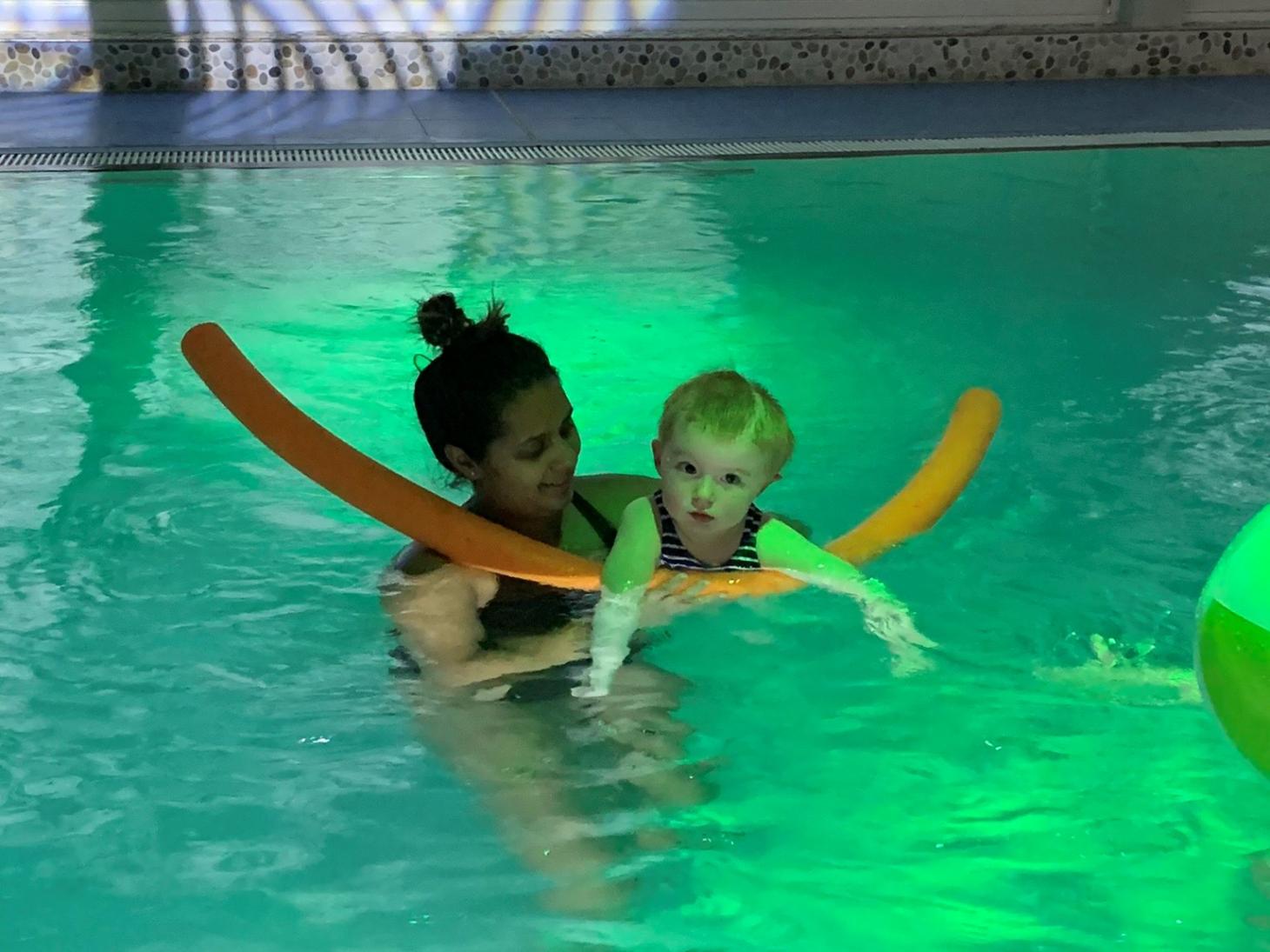 Millie in the pool swimming with the support of a therapist