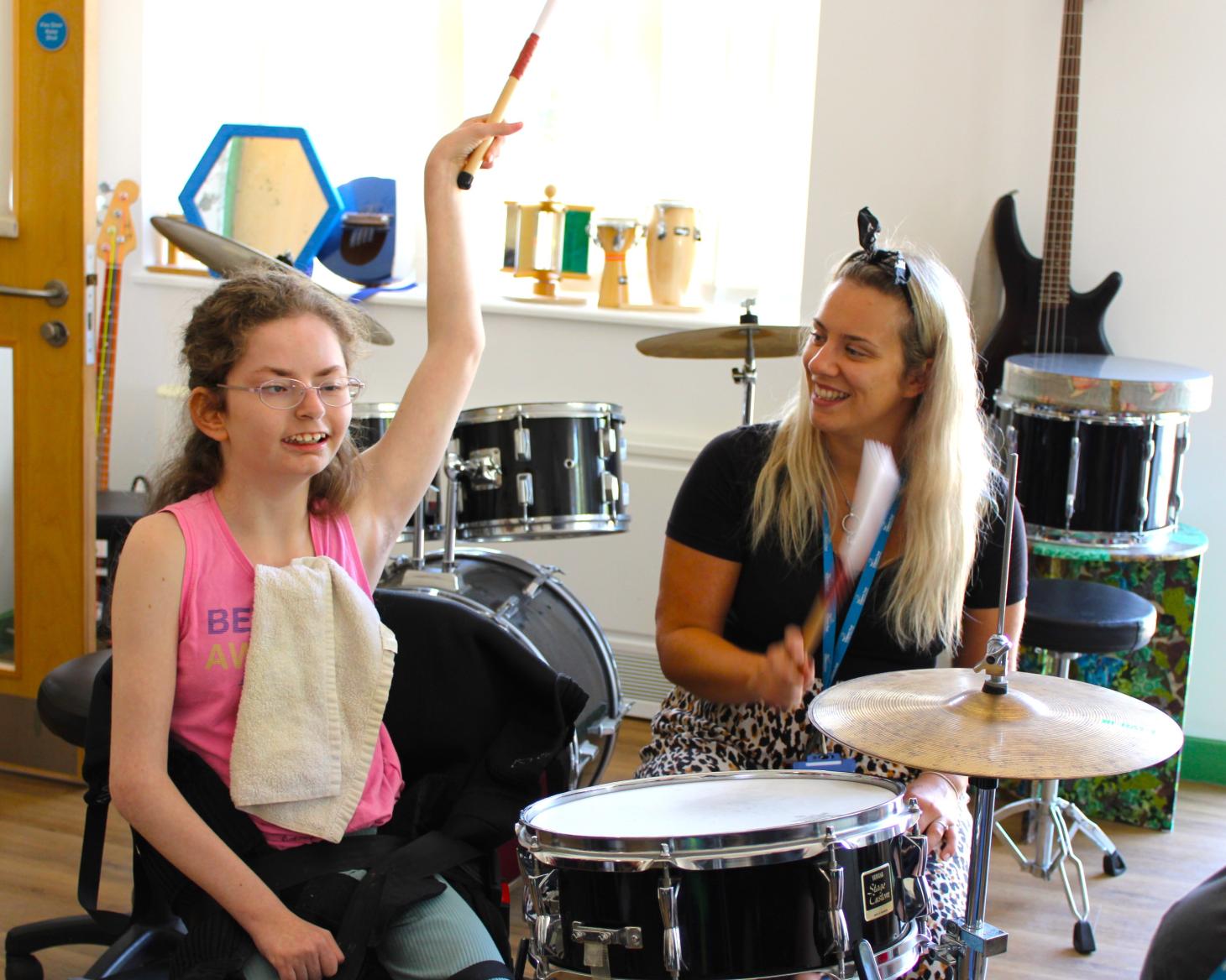 Young person playing the drums with Music Therapist