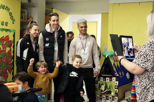 Fulham FC football players posing for photo with two young boys