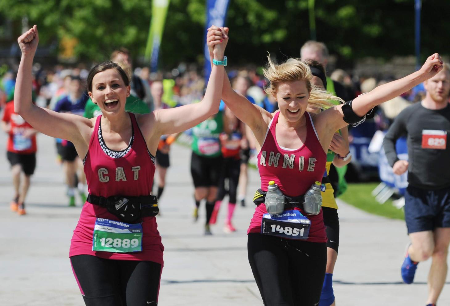 Two marathon runners holding hands celebrating