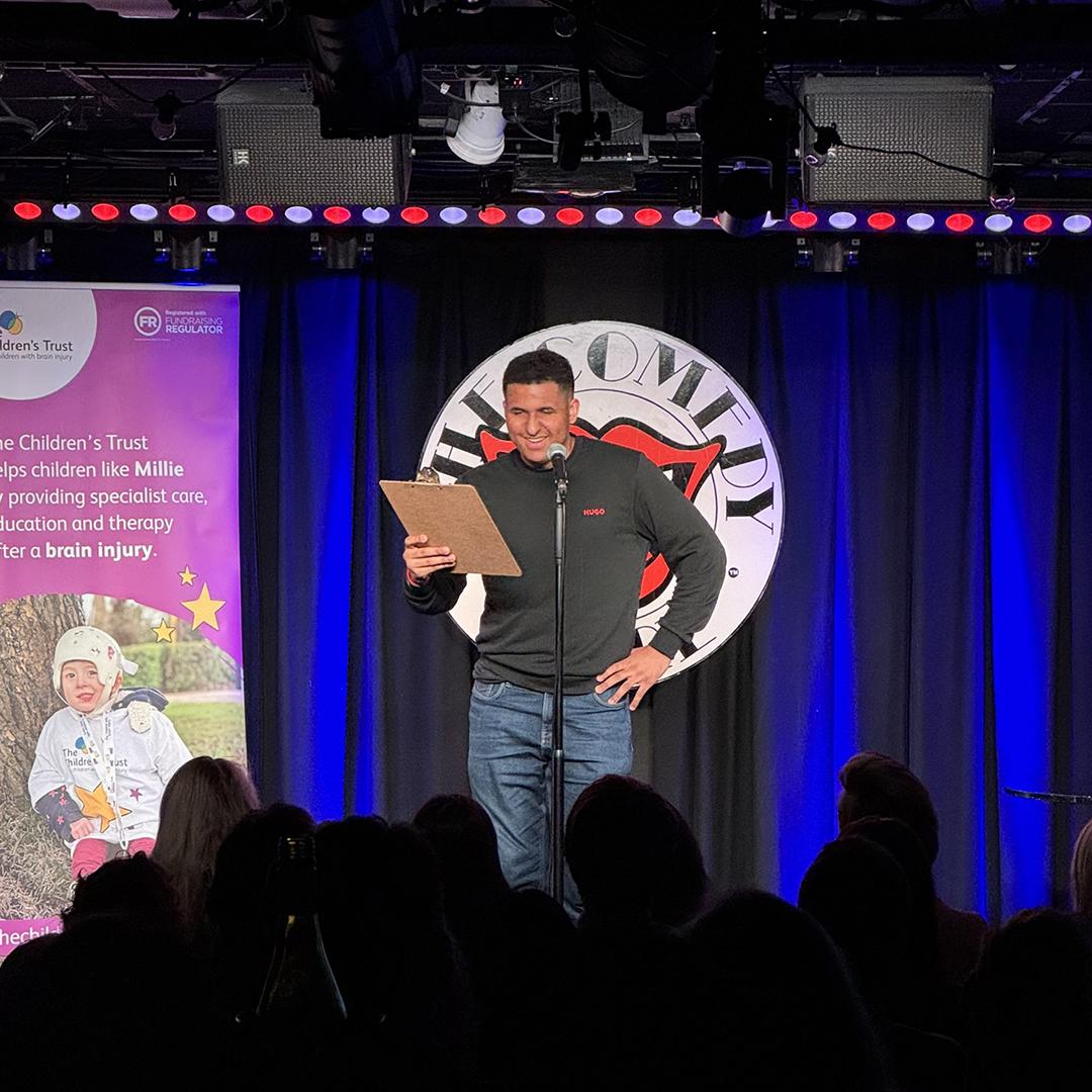 Zac on stage in front of The Comedy Store sign