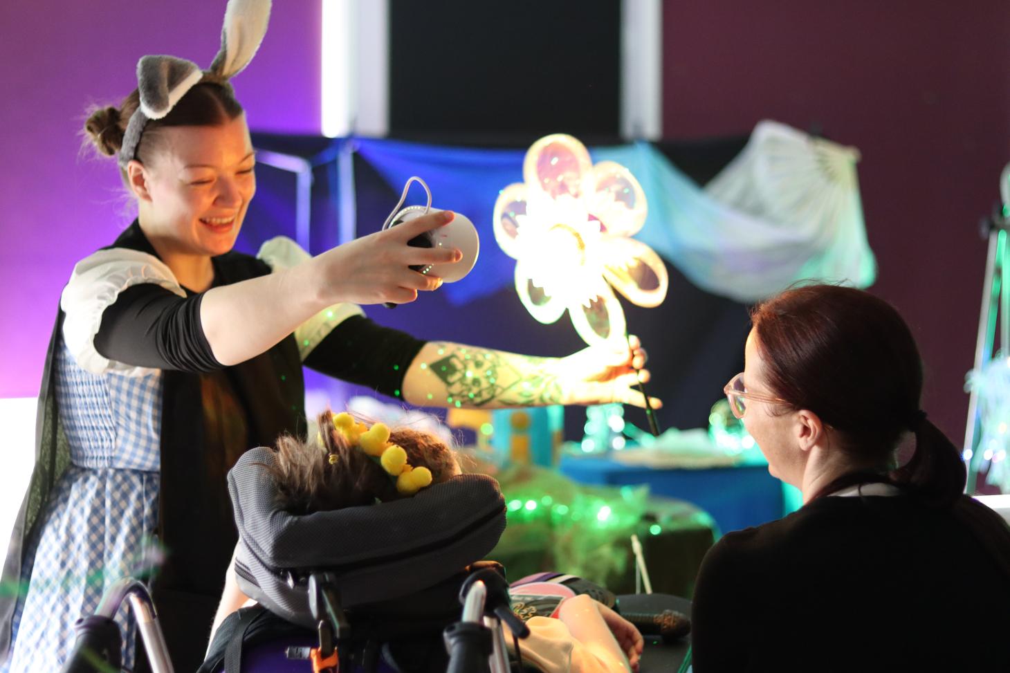 performer holding up a lit-up flower in front of a child