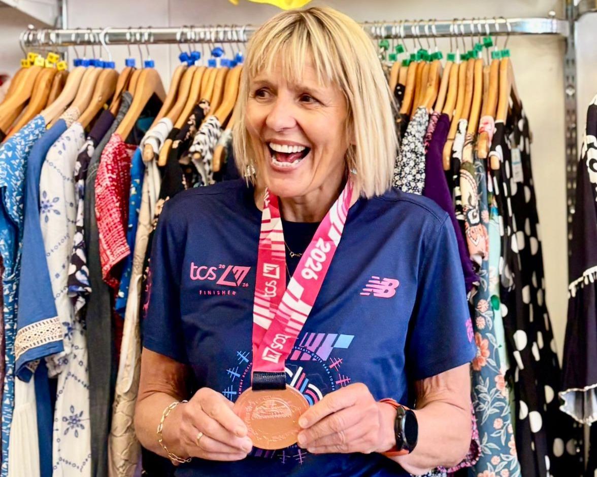 Sally smiling in the charity shop with her marathon medal