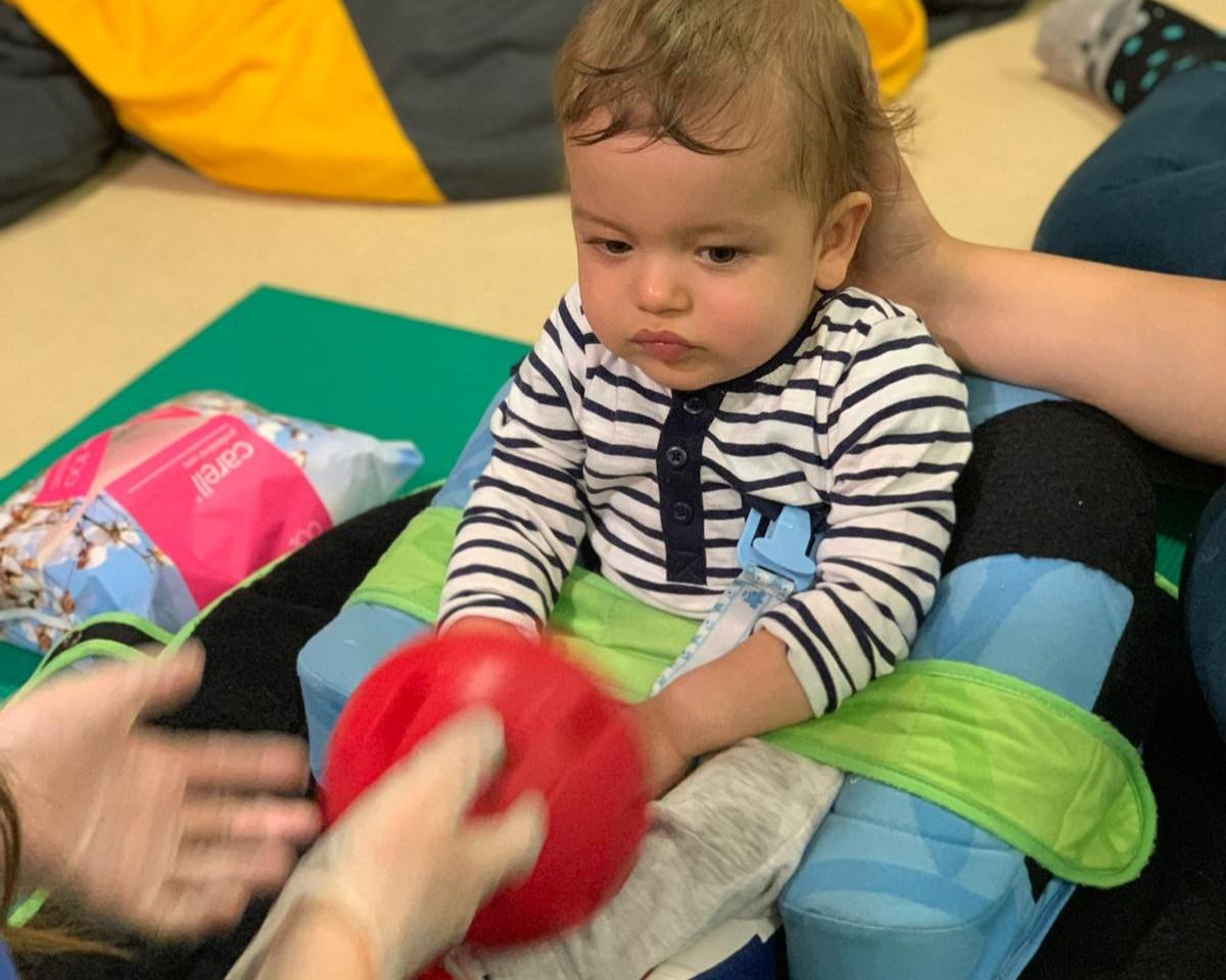 Seb as a baby in a therapy session looking at a ball