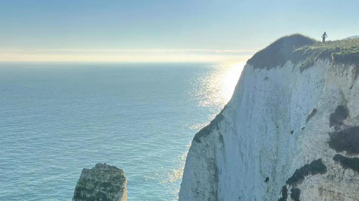 beautiful blue sky with sun reflecting on the baby blue sea surrounding white chalky cliffs