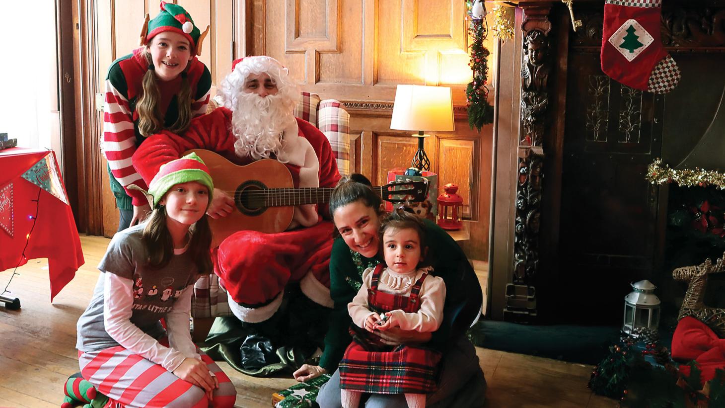 A mother and daughter visiting Santa and his elves in Santa's Grotto.