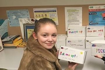 heidi: girl holds up box that reads 'pick me up' 
