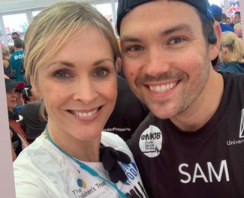Jenni Falconer and Sam Attwater smile at the camera wearing running gear