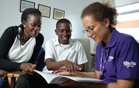 stroke association staff member shows book to adult and young person 