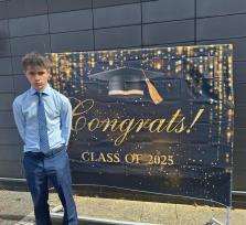 Jake standing in front of a graduation banner