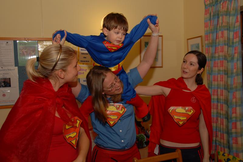 Tommy in a superman costume with staff at The Children's Trust