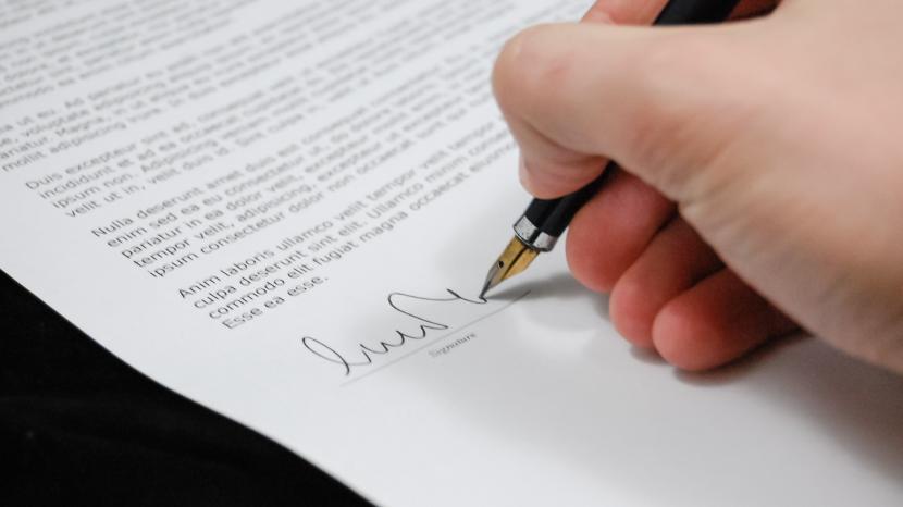 An image of a hand signing a legal document 