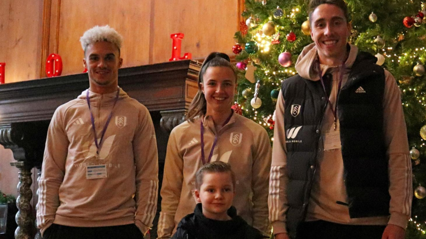 Fulham FC football players with young boy in front of Christmas tree