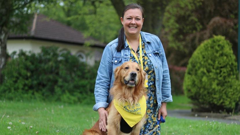 Lee and her PAT dog Mac, sitting outside on the grass