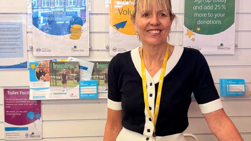 Volunteer charity standing smiling in our charity shop