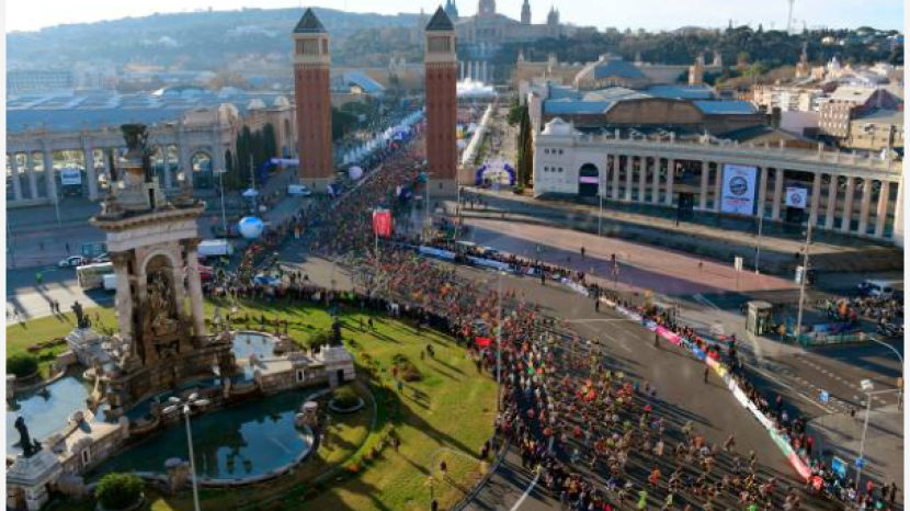 marathon runners streaming through the historic town in Barcelona with large fountain monument