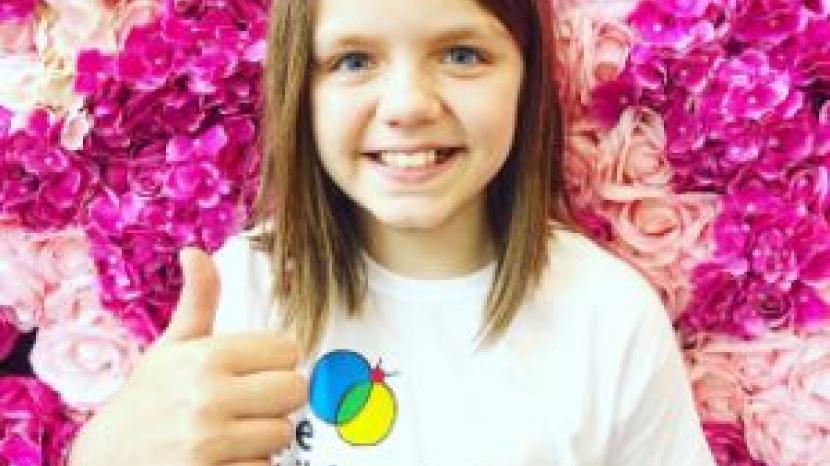 Issy: young girl smiles and gives a thumbs up