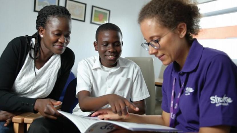 stroke association staff member shows book to adult and young person 