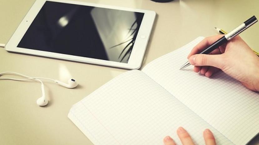 a hand holds a pen writing in a notebook