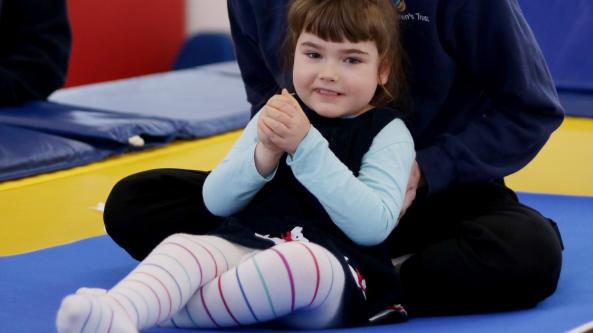 Olivia sat on the trampoline during a rebound therapy session at The Children's Trust